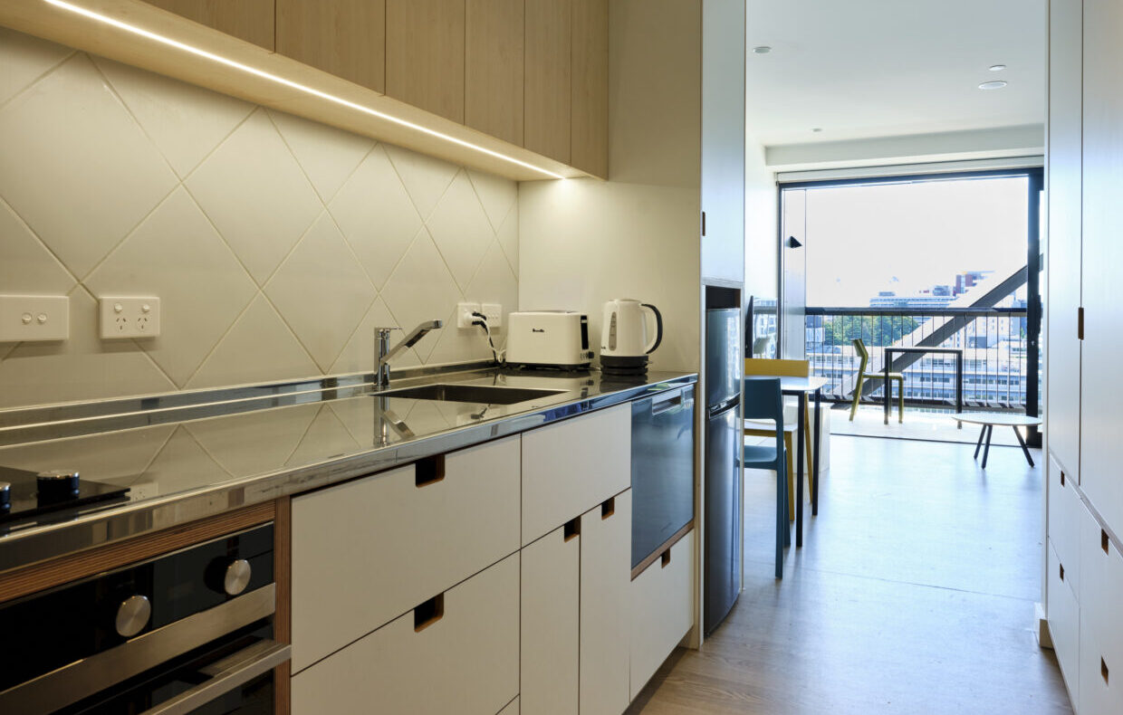 The view along a kitchen to a large window in a studio apartment at HomeGround, Auckland City Mission