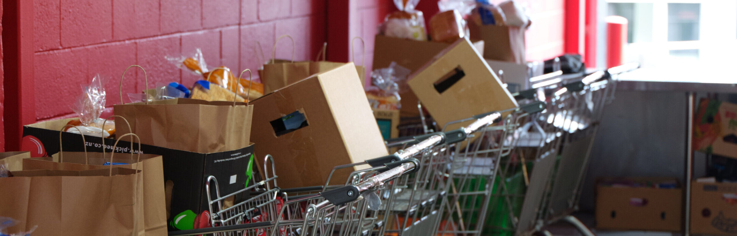 Trolleys with food parcels lined up against a red brick wall