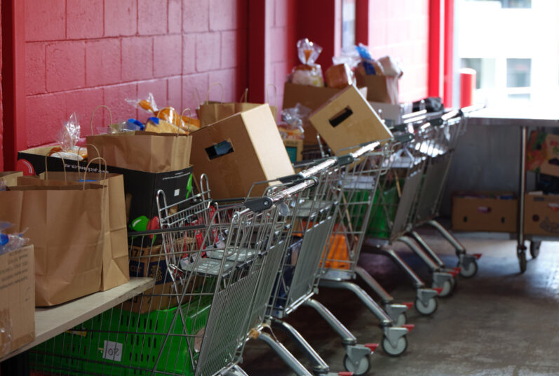 Trolleys with food lined up against a red brick wall.